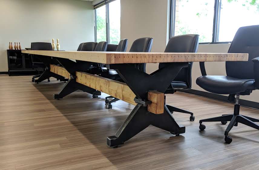 board room table made from reclaimed bowling lane on industrial trestle base