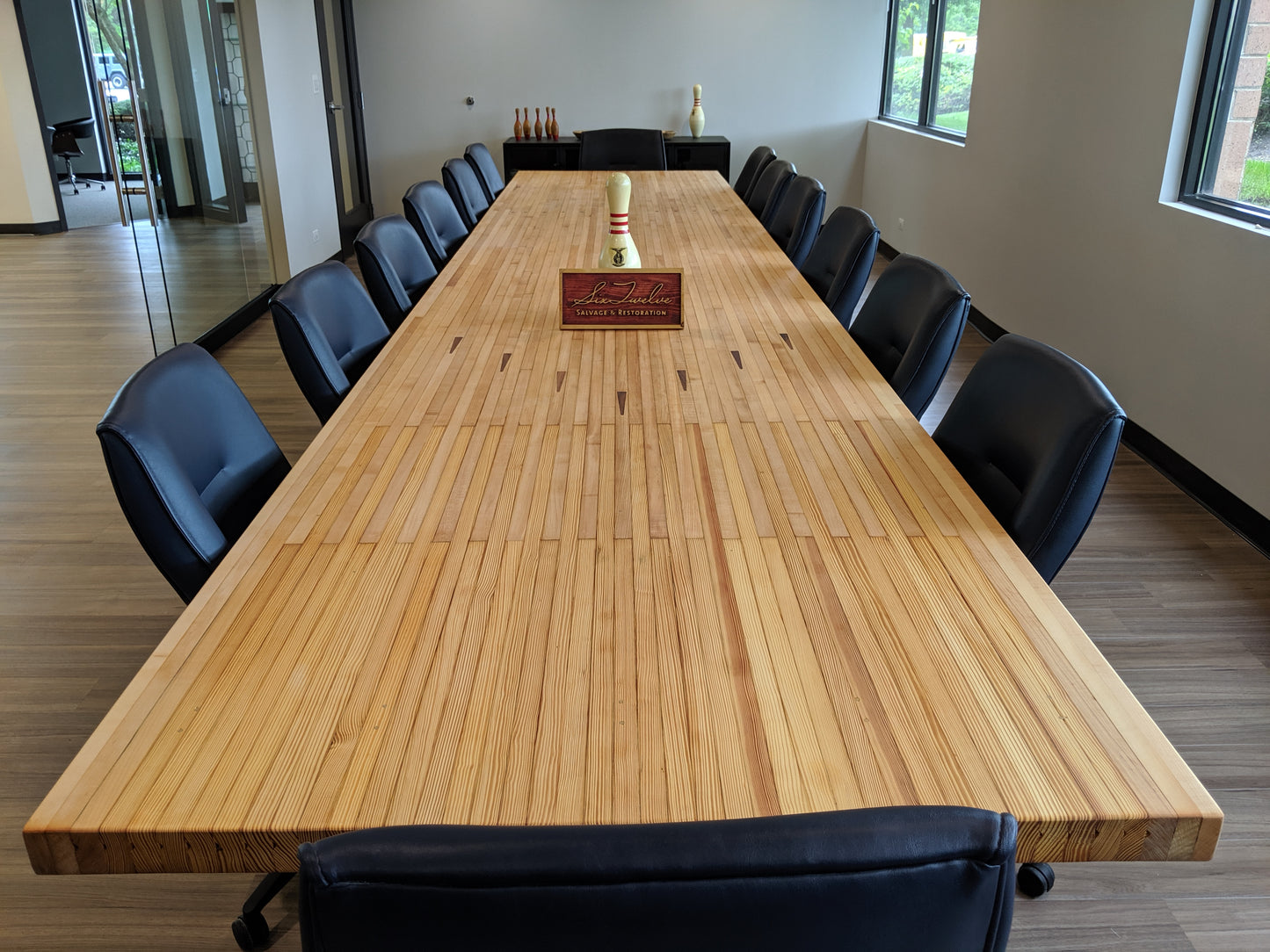 board room table made from reclaimed bowling lane on industrial trestle base